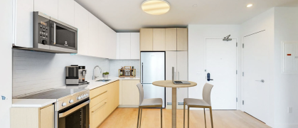 NYC apartment interior with wood floor, stainless steel appliances and barstools